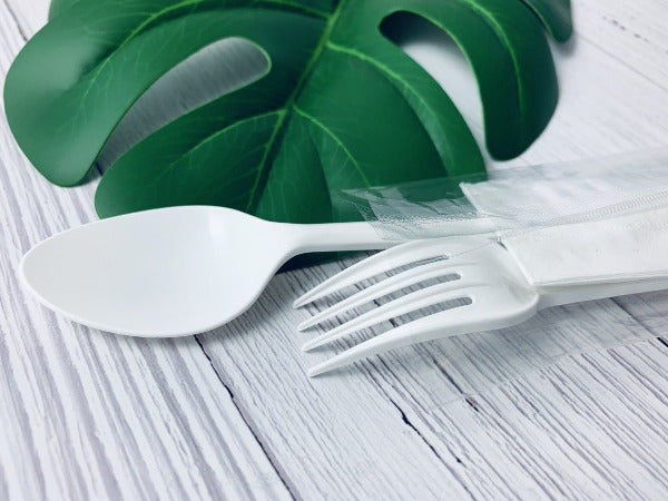 Spoon and fork on a wooden white table with a leaf